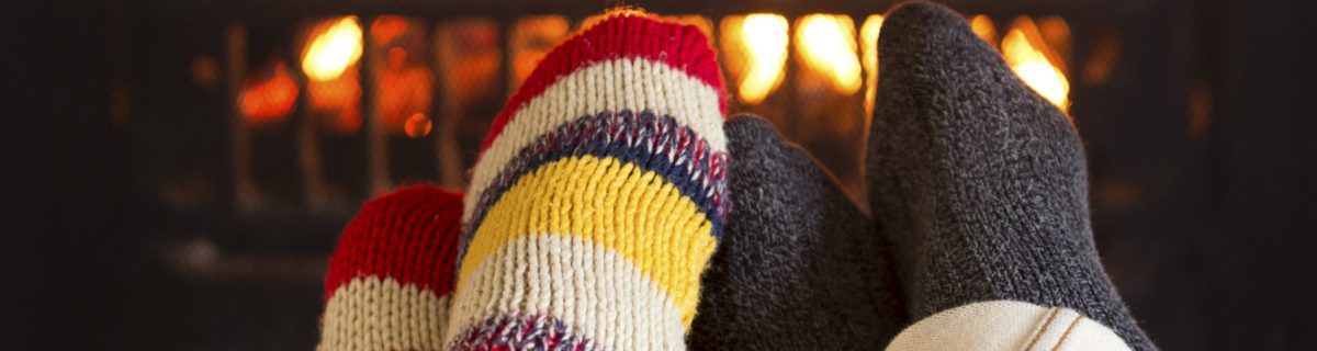 Couple's feet in woolen stocking in front of fire warming up