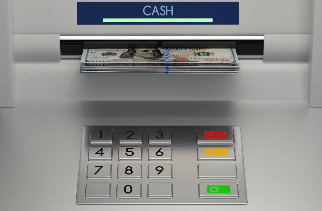 Photo of ATM with $100 bills coming out of a slot.